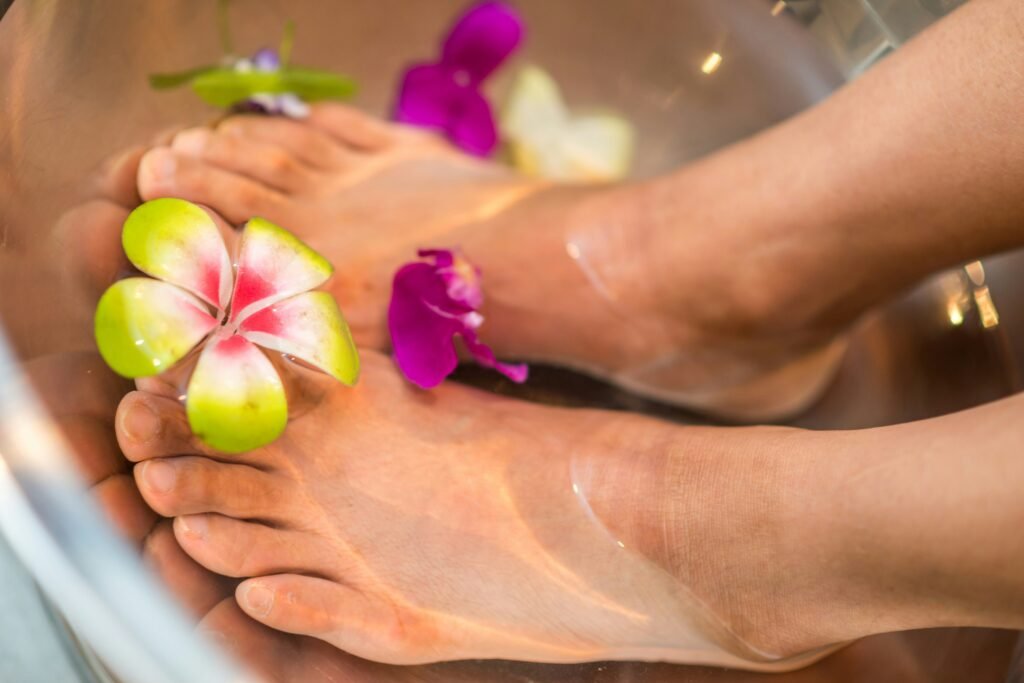 Light-skinned feet soak in water with flowers for a DIY spa day